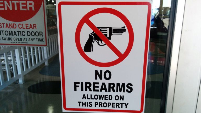 A "no firearns" allowed sign posted on a business door.