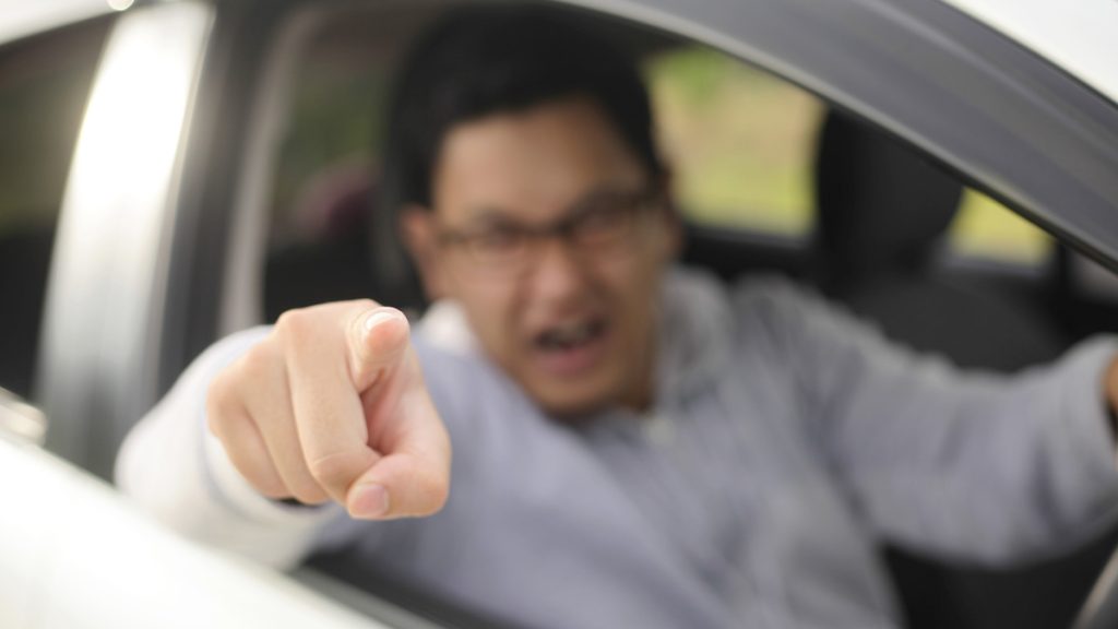 An angry driver screaming and pointing at another driver.