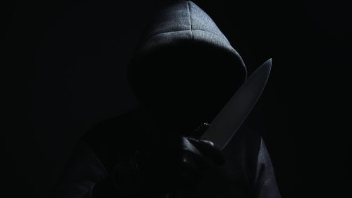 A criminal wearing a hood and holding a knife